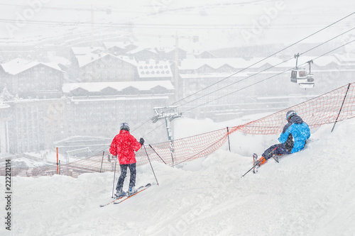 Two skiers have a rest on a slope during a heavy snowfall