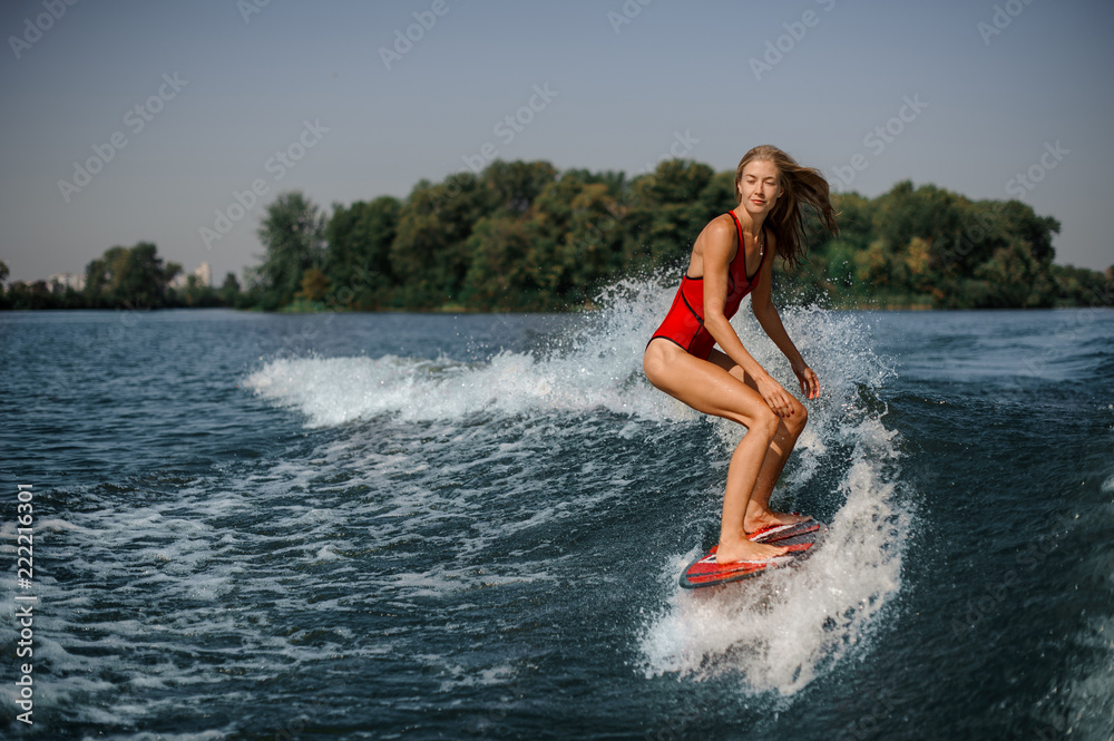 Blonde girl standing on the red wakeboard Blonde girl standing on the red wakeboard