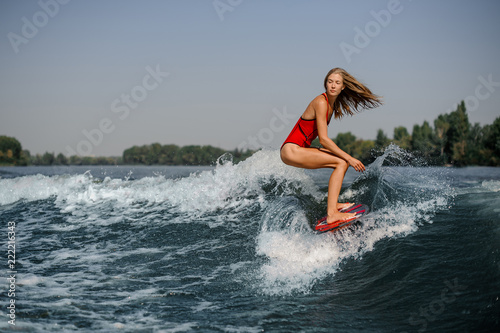 Attractive blonde girl riding on the red wakeboard