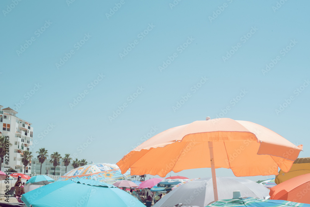 Imagen veraniega de sombrillas coloridas en una playa llena de gente frente a un mar en calma un día de verano despejado
