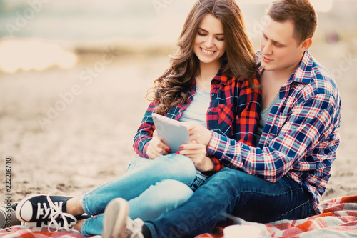 Loving couple using a tablet on the beach