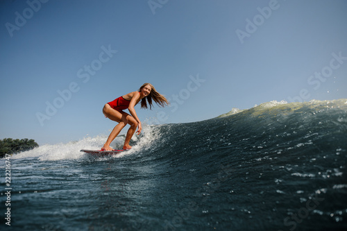 Blonde girl riding on the wakeboard on the lake