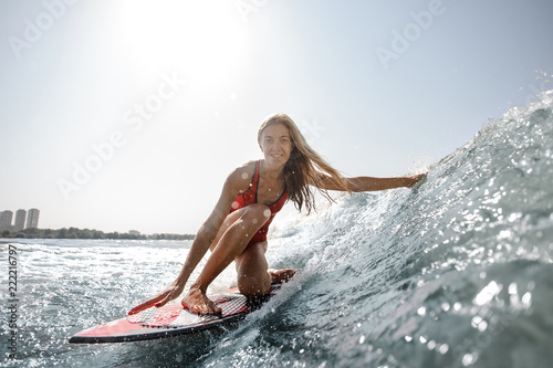 Smiling blonde girl standing on the wakeboard and looking at camera