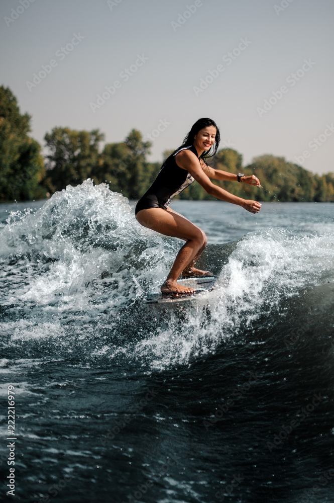 Brunette girl riding on the wakeboard on the bending knees