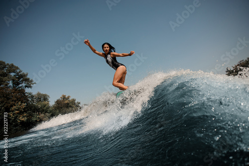 Sexy brunette girl riding on the wakeboard near the lakeside