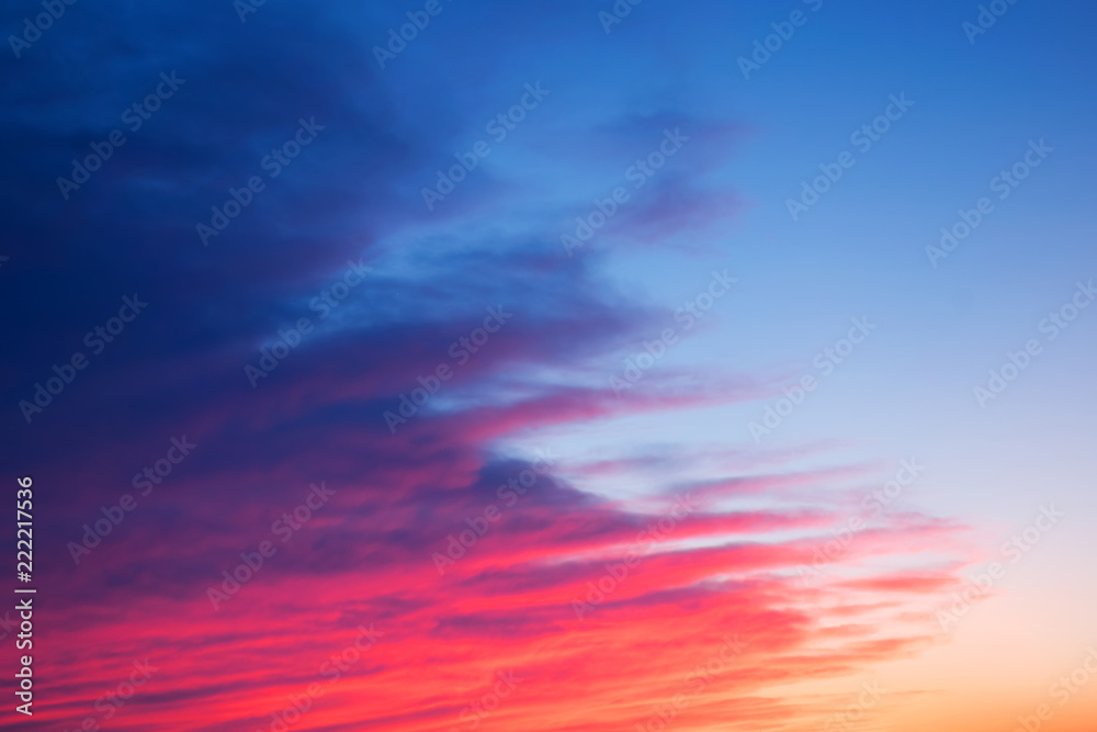 Red, pink and blue bright sunset with beautiful diagonal clouds. Bright evening sky with layered clouds. Night is Near Bright Illumination