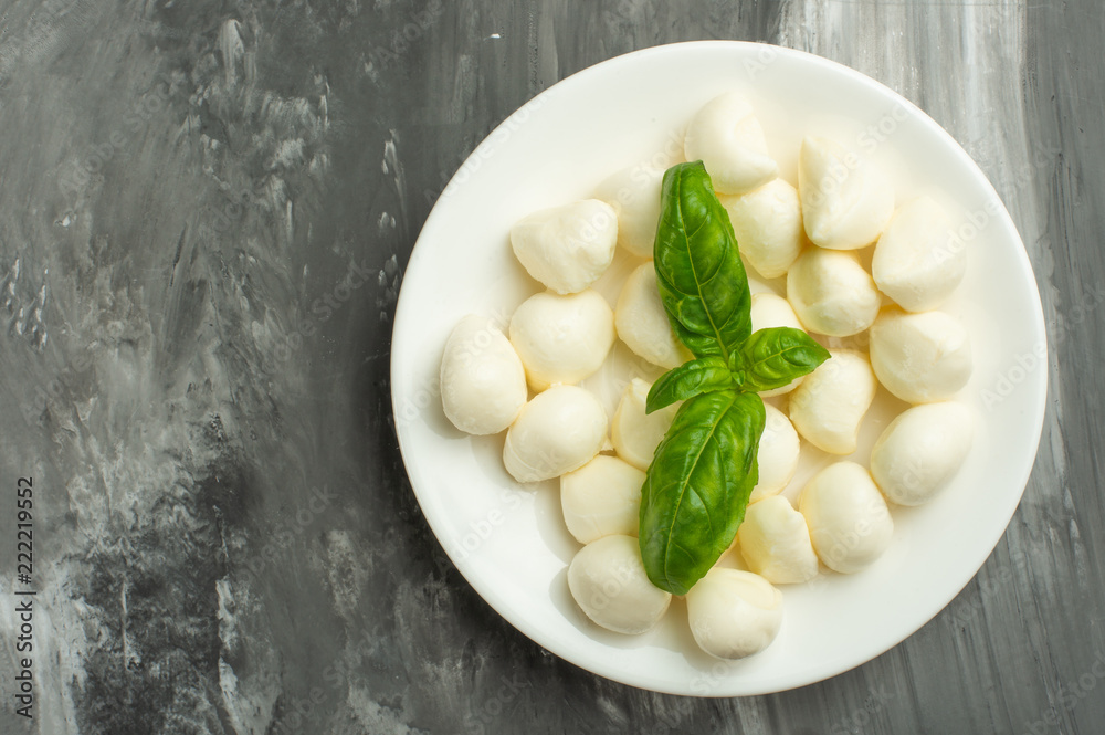 Mozzarella with basil leaves - fresh ingredients for caprese salad with copy space on dark background, top view Mozzarella with basil leaves - fresh ingredients for caprese salad with copy space on dark background, top view