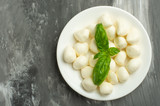 Mozzarella with basil leaves - fresh ingredients for caprese salad with copy space on dark background, top view