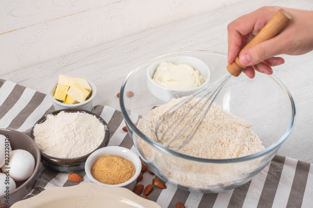 Chef  mixing flour and dough for cooking sweet cake with cooking ingredients on kitchen table