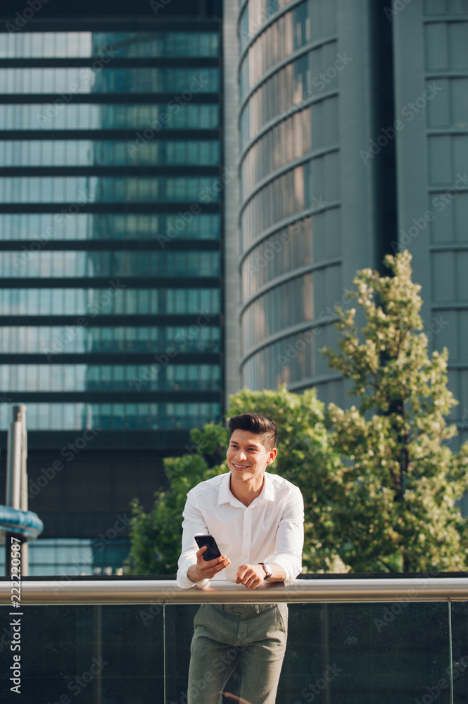Young man with smartphone leaning on railing Young man with smartphone leaning on railing