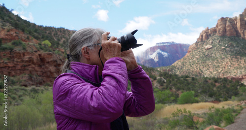 Senior female photographer taking pictures of sandstone canyon in Zion Utah