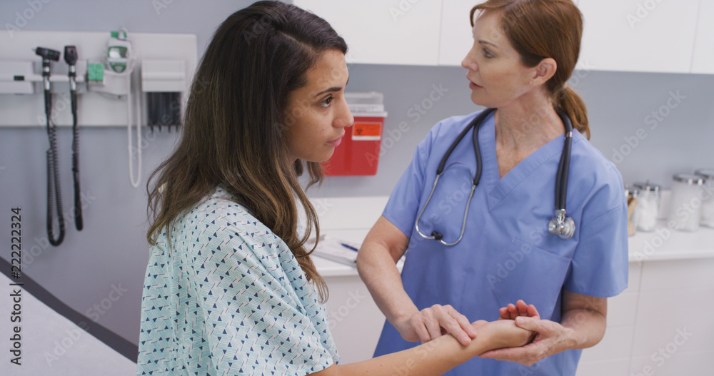 Fototapeta premium Medical nurse checking pulse of young patient indoors medical clinic. Close view of nurse using fingers to monitor patients vital pulse