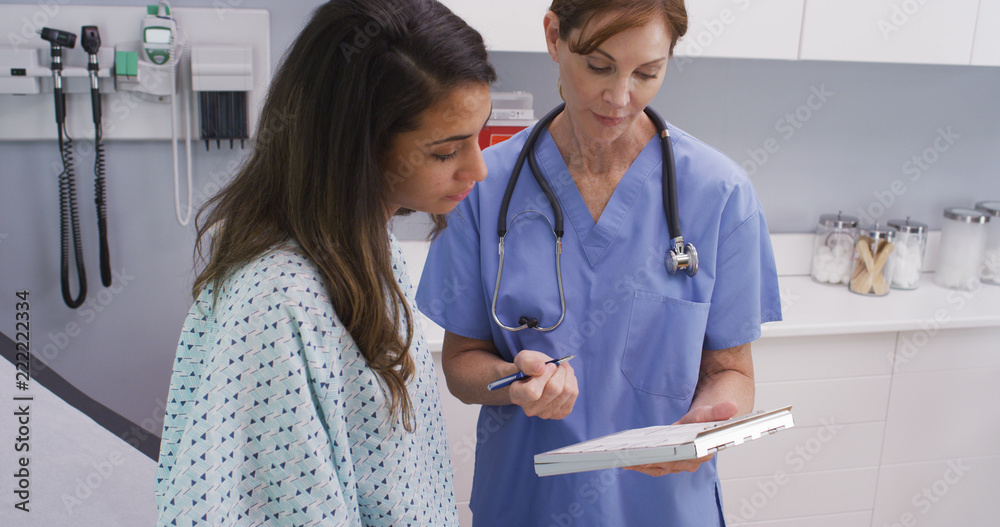 Φωτογραφία Close-up portrait of medical nurse checking medical history with young latina patient