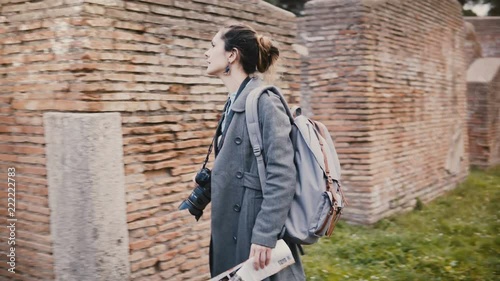 Camera follows young excited traveler woman with backpack expolring ancient historic red brick ruins of Ostia, Italy. photo