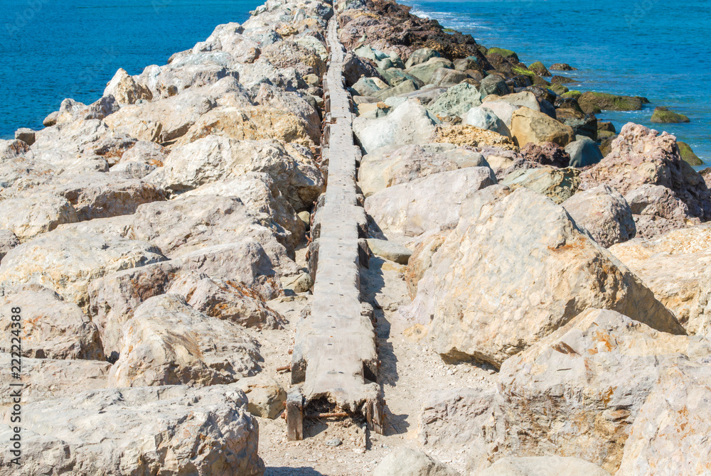 rocky breakwater in the Pacific ocean at Santa Barbara harbor with a narrow path on the top