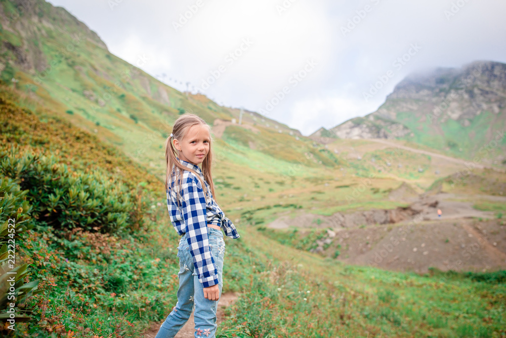 Beautiful happy little girl in mountains in the background of fog