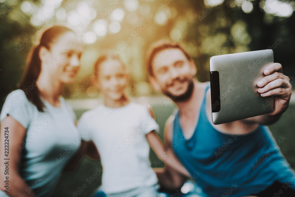 Obraz premium Happy Young Family Using Tablet in Summer Park.