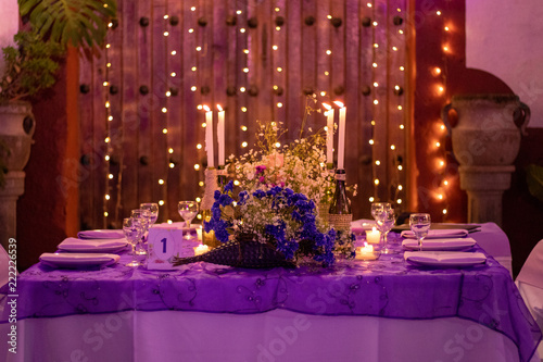 Party table decorated with lights in the background and candles © Arturo