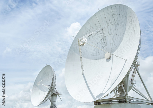 large white satellite dishes turn up skyward on blue sky in communication antenna system center station