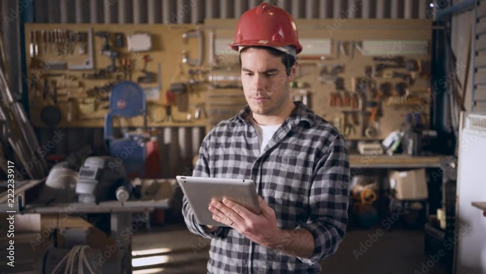 white contruction worker working on a tablet in a workshop using the wifi white contruction worker working on a tablet in a workshop using the wifi