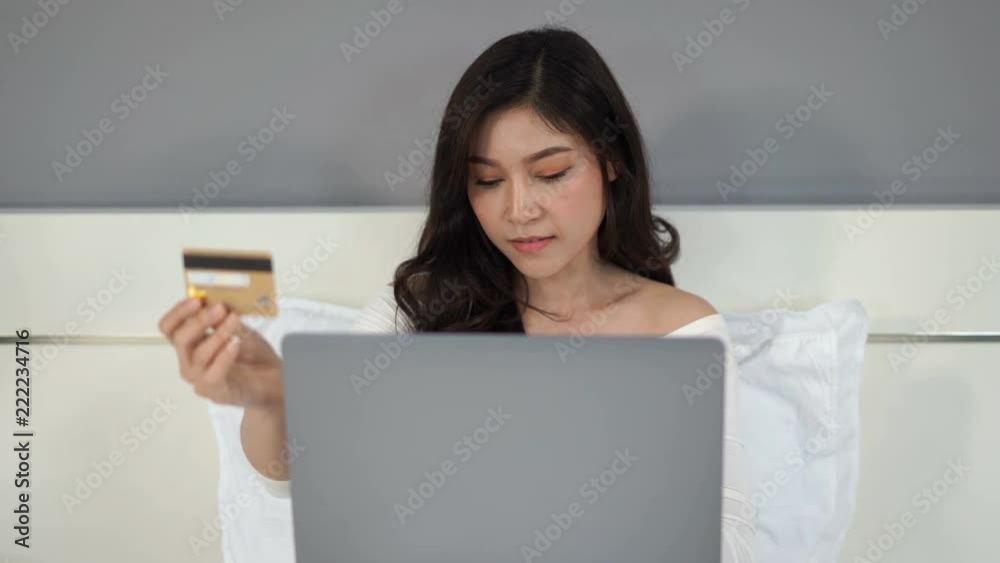 woman shopping online with credit card and laptop computer on a bed woman shopping online with credit card and laptop computer on a bed