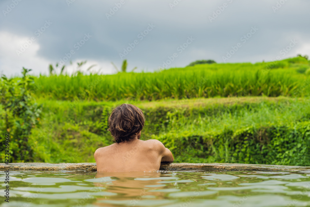 Man tourist in Belulang Hot Springs in Bali on the background of rice terraces