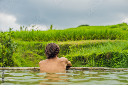 Man tourist in Belulang Hot Springs in Bali on the background of rice terraces © galitskaya