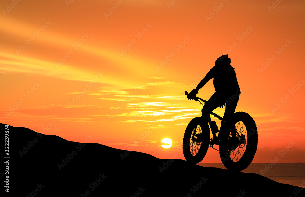 Fototapeta premium Silhouette man and bike relaxing on blurry sky background.