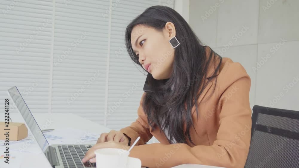 Asian business woman busy in work with laptop computer and call phone to somebody Asian business woman busy in work with laptop computer and call phone to somebody