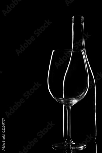 Empty glass bottle with glass isolated on a black background. Copyspace