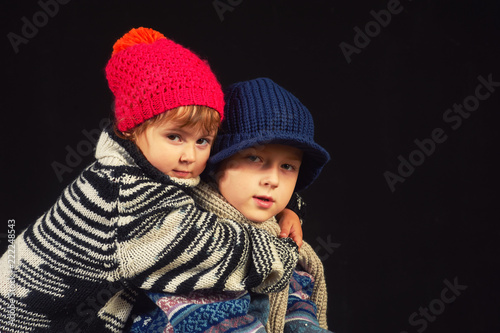 children in warm knitted hats on a dark background . Brother and sister in warm sweaters