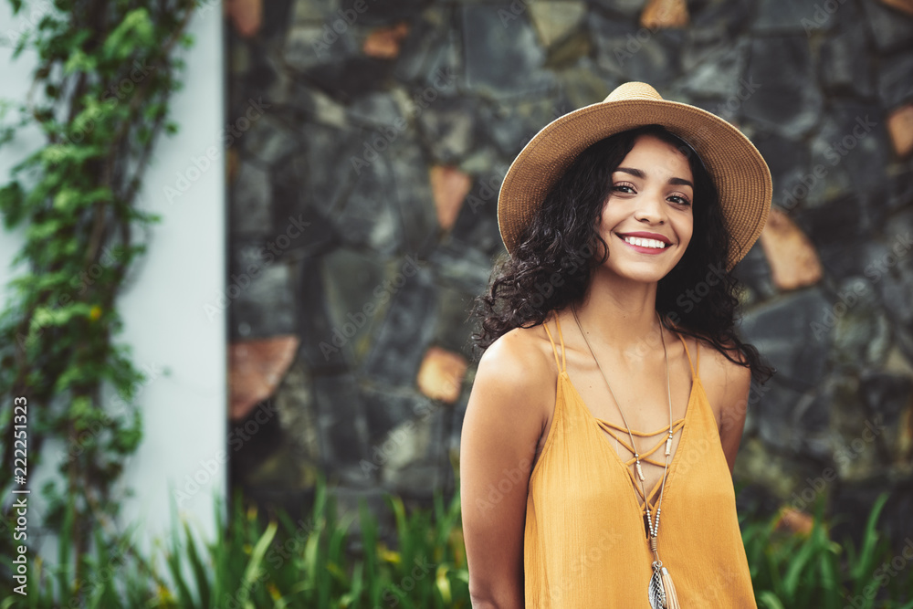 Fototapeta premium Very beautiful young Hispanic woman in straw hat smiling at camera