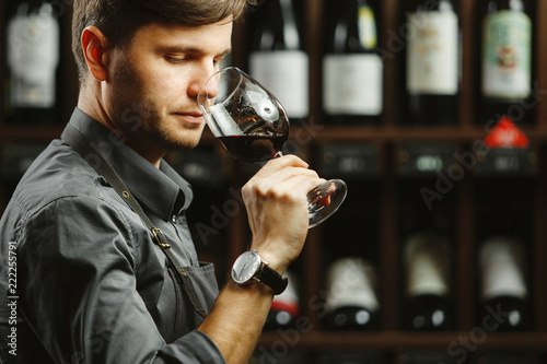 Bokal of red wine on background, male sommelier appreciating drink photo