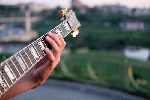 hand of guitarist perfoming chord on a grif of electric guitar, outdoors photo