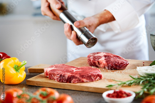 Man using pepper grinder to season steak