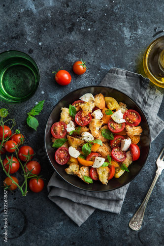 panzanella, traditional italian tomato, mozzarella and bread salad in black bowl, top view