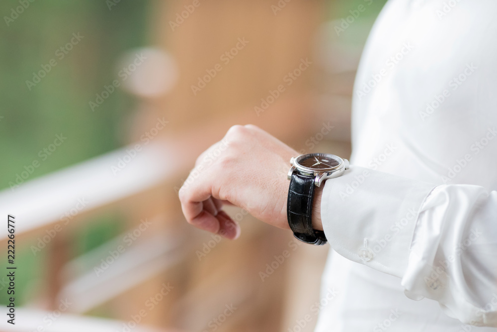 Businessman checking time on his wristwatch. men's hand with a watch Businessman checking time on his wristwatch. men's hand with a watch