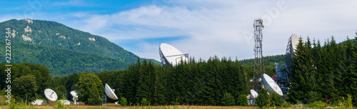 Big satellite dish antennas hidden in green pine tree forest. Satellite Communication Center in Cheia, Prahova, Romania