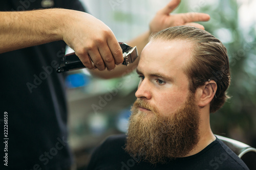 Handsome man Getting Haircut By Barber While Sitting In Chair At Barbershop