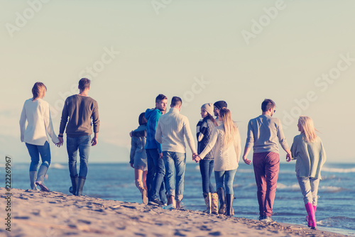 Group of friends running on beach during autumn day