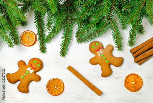 Gingerbread men and Christmas tree branches on wooden background