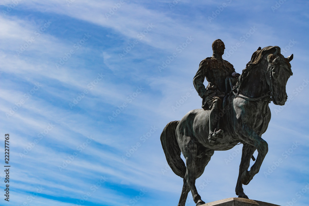 Statue of man riding a horse under blue sky with lines of clouds Statue of man riding a horse under blue sky with lines of clouds