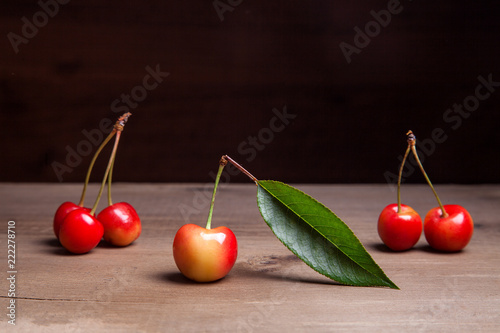 Yellow sweet cherry with green leaf on wooden background.