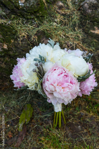 Bouquet made of pink and white pionies lies on a green lawn photo