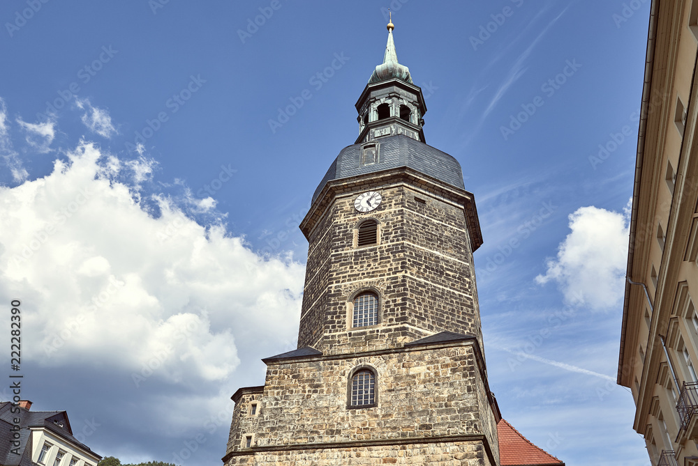 low angle view of old historical church of St John with clock against blue sky in Bad Schandau, Germany low angle view of old historical church of St John with clock against blue sky in Bad Schandau, Germany