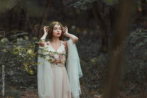 fantasy girl with elf ears in flower dress posing in forest