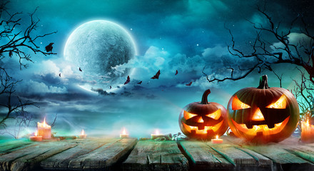 Halloween - Jack O' Lanterns And Candles On Table In Misty Night
