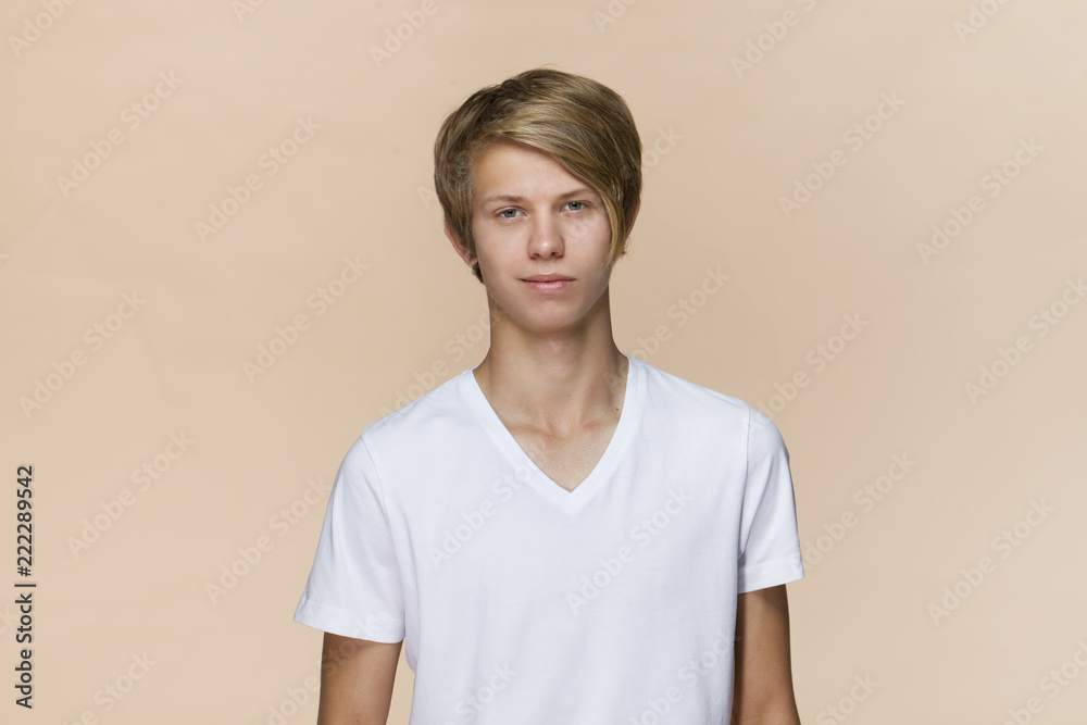 Portrait of a handsome teenager smiling at the camera. Isolated on brown background