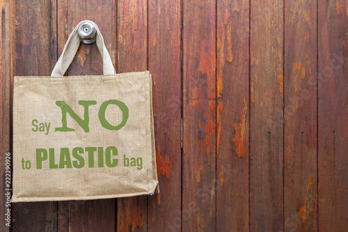 Jute bag with No plastic logo hanging on old wooden wall, ecological object concept