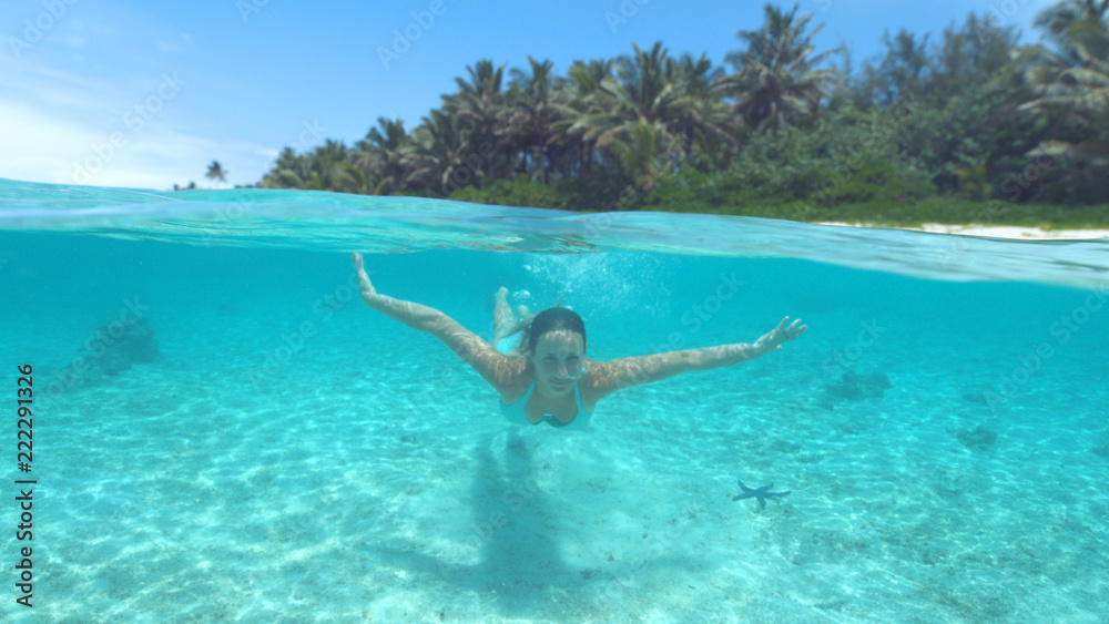 CLOSE UP Happy young woman diving in the turquoise water on a perfect summer day
